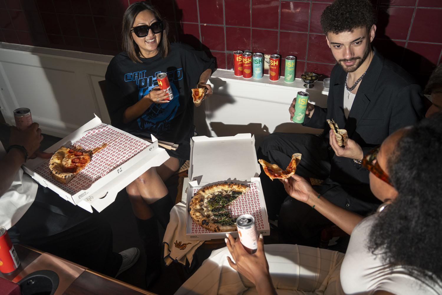 People drinking alcohol-free drinks and eating pizza